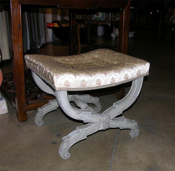 A Painted Louis XVI stool. Crossed, bent legs with acantus decor, a fluted turned stretcher, and upholstered seat.