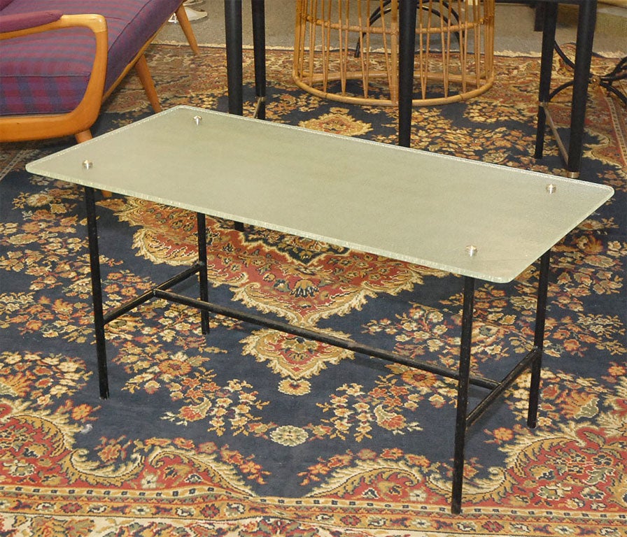 Élégante table basse française avec plateau en verre et cadre en fer forgé dans le style de Pierre Guariche.