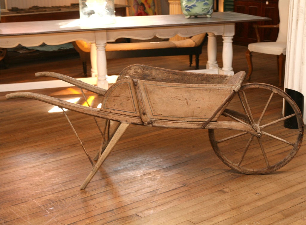 beautifully designed and constructed wheelbarrow<br />
probably by a New York State Carriage Maker<br />
original painted tan with blue and brown pinstriped surface<br />
removable side panels<br />
mortised construction<br />
wrought iron