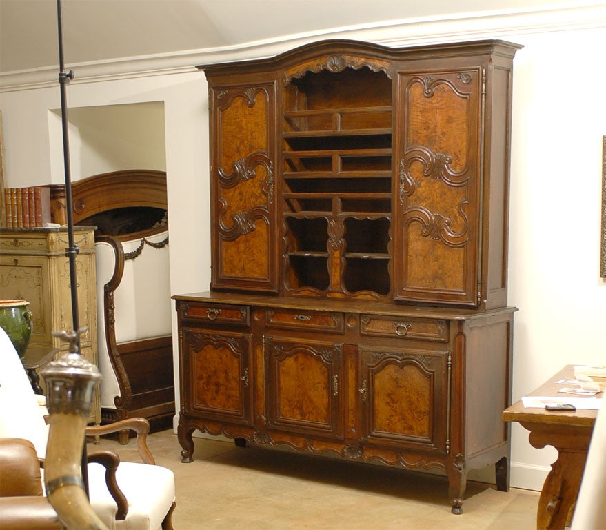 A French restoration period early 19th century walnut vaisselier from the Bressan region with bonnet crest, molded doors with burl wood inset panels and multiple shelves. Born in the eastern area of France during the first quarter of the 19th