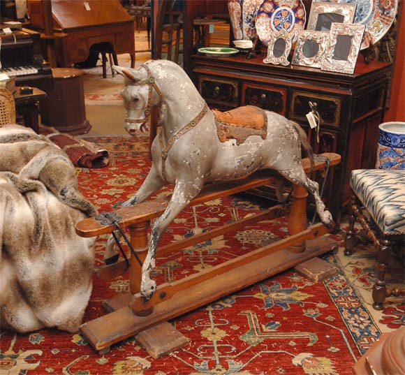 With a handcarved elm wood painted equus, with leather saddle and dressing and a horsehair tail, mounted on a carved oak platform, all with original patina.  The rocking mechanism is in good order.    This item came from a Loire Valley chateau, was