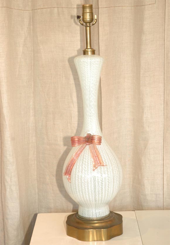 SINGLE WHITE MURANO LAMP WITH A PINK BOW AND BRASS BASE.