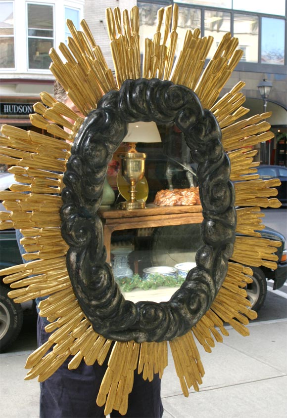 A gold and silver gilt carved wood sunburst mirror.