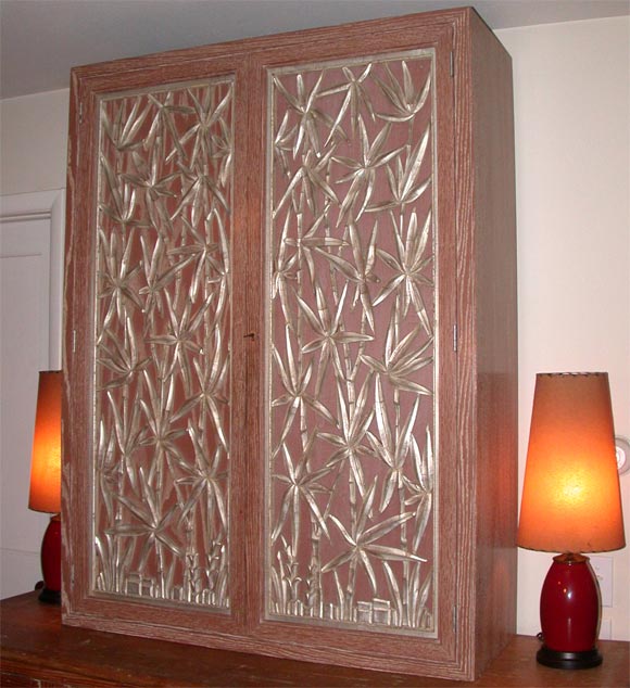 Spectacular limed oak wall cabinet with silver leafed carved bamboo door panels and two interior adjustable shelves.

