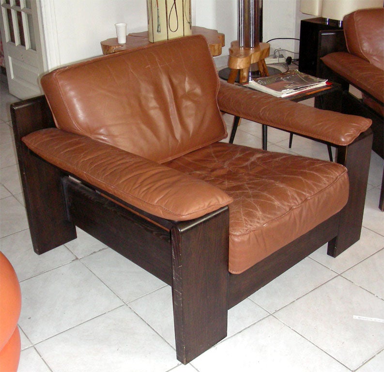 1970-1980 brown leather sofa and two matching armchairs with dark stained pinewood structure. Armchairs height 70/37 cm., length 96 cm., depth 92 cm.