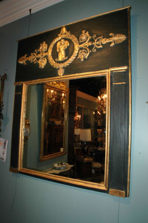 Empire painted trumeau mirror with neoclassical detailing, including winged cherub, in dark green and gold.
