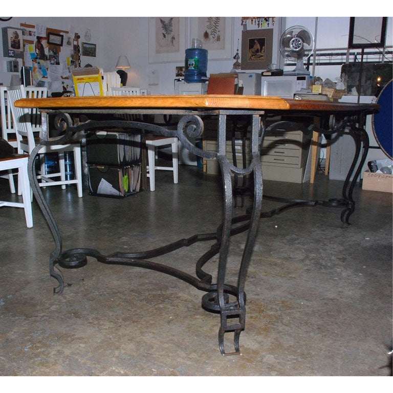 A wonderful iron and oak dining table with a plank top and sculpted iron base. The table has two unfinished extension leaves each measuring 24
