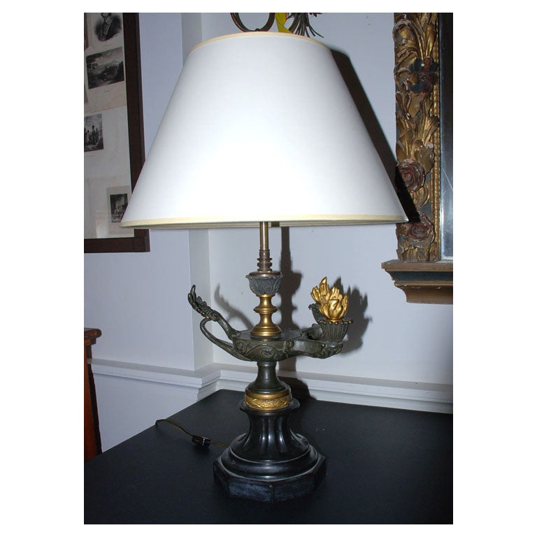 A bronze decorative oil lamp with flame finials and a fluted marble base converted into a table lamp. Shade not included.