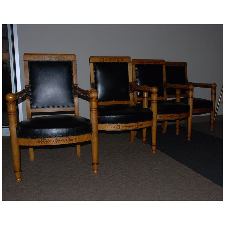 Set of four 19th century black leather upholstered Charles X armchairs with inlaid backs and aprons.