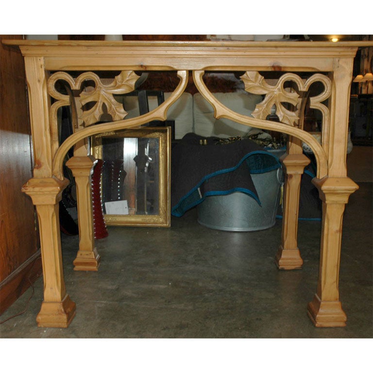 A unique carved Gothic console table with a plank top and carved leaf apron.