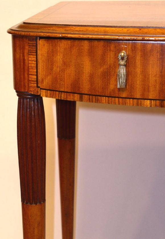 An Art Deco period side table having walnut and Coromandel wood veneers with ebony inlays. One drawer with brass drop pulls. The legs with reeded decoration, England, circa 1935.