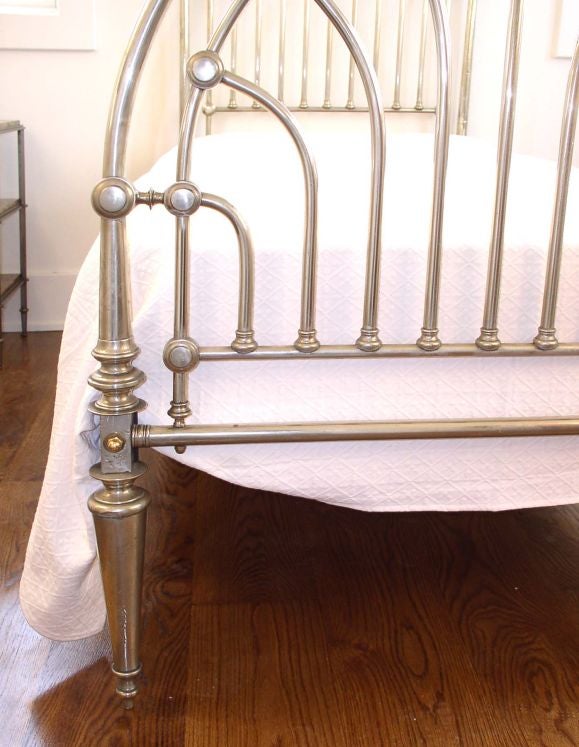 An Art Deco period metal twin size bed with nickel plated and clad headboard and foot-board. Fits a twin size mattress. Supplied with later cast iron angle support rails with brass capped bed bolts and mattress platform. Mattress platform is