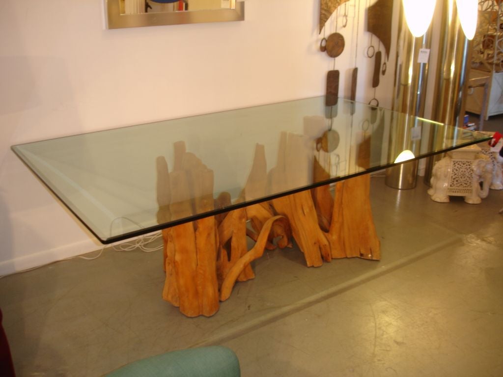 A beautiful glass top dining table with a cypress base. The base is signed but is hard to read. Base has a beautiful organic flow. Base is substantial. Measurements are of glass top.