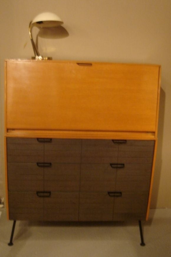 A drop-front desk over drawers designed by Raymond Loewy for Mengel.  Circa 1940.

Features polished wood case complemented by smoked gray oak drawer fronts and painted black wrought iron legs and hardware.

Interior of desk features the