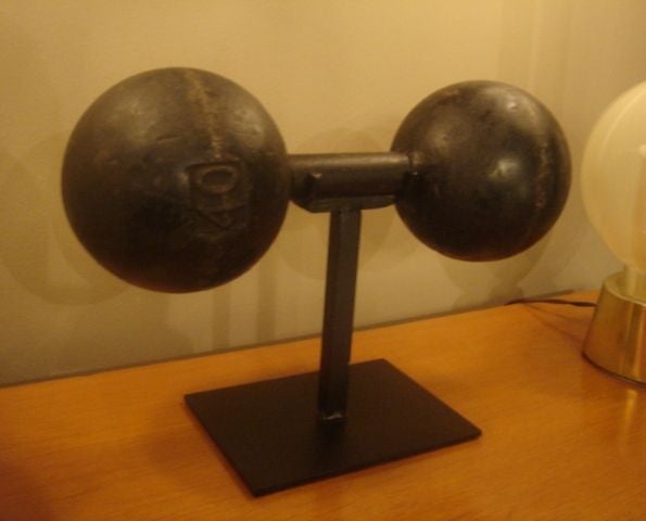 A sculptural antique iron dumbbell mounted on a custom metal base. Weighs 40 pounds--