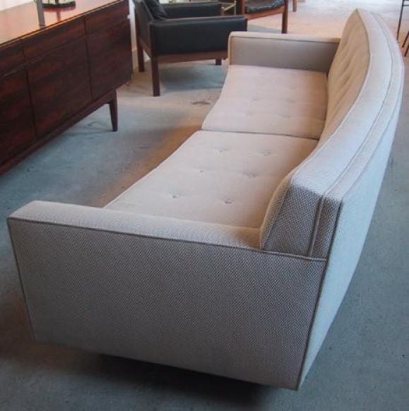 THIS ITEM HAS BEEN SOLD.  A curved sofa designed by Edward Wormley for Dunbar.  Features a modified Tuxedo style with drop arms, tufted back and cushions, and dark stained square mahogany feet.  Upholstered in a beige/off-white fabric.