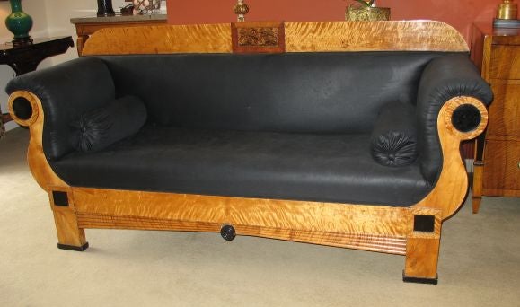 Elegant and architectural Biedermeier sofa with removable back rail. The frame covered in satin birch with ebony details. The central rectangular panel framed in mahogany with burled elm.