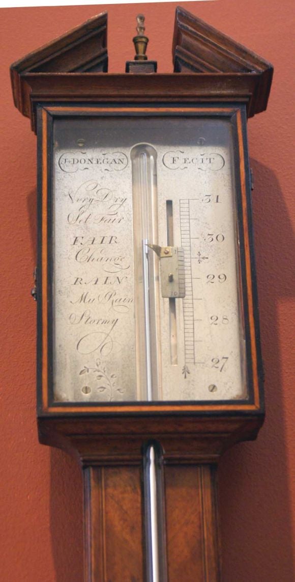George III mahogany stick barometer made in England about 1790.  The case features a broken pediment and silvered register.  The piece was made by J Donegan.  The case is decorated with inlay.