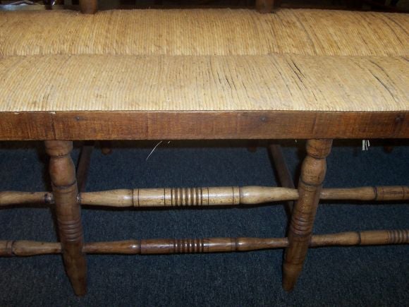 A very sturdy and good-looking bench, very straight-backed. The rush seat is hand-rushed and in very good condition.  This is a very natural colored fruitwood.