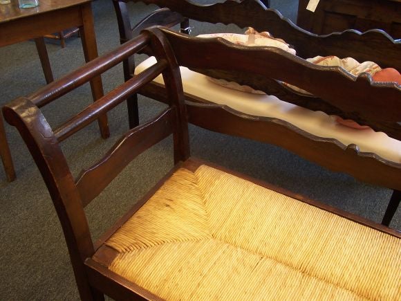 Antique bench from France with a rush seat. Lovely shaped rails and curved arms give this bench all the right elements.