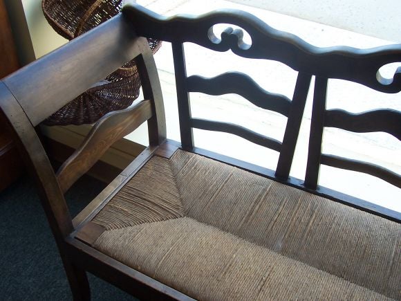 Antique rush seat bench from France. Three seat back with shaped rails and beautifully curved arms. Great patina.