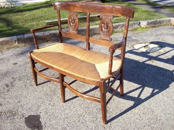 Very decorative carved rush seat bench from France. The beech wood has a lovely color and patina. Beautifully carved leaf motif on the back, shaped rails, and curved arms with turnings on the supports. Seats two comfortably.
