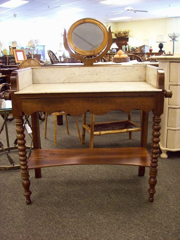 Antique washstand from the Loire Valley with a marble top and a small round adjustable mirror. The turned legs, shaped drawer front, and decorative towel rails all embody the essence of country French. Base is made of fruitwood. Original marble.