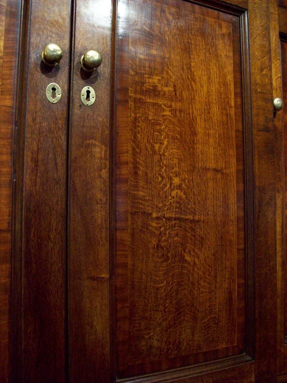 An outstanding period Welsh housekeeper's cupboard. The color of the oak panels and mahogany banding is exceptional. There is a unique carved molding on the top that we have never seen before. Original knobs and hinges. At 7 1/2' wide, this