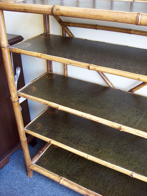 Large antique bamboo bookshelf from England with an open back. The five shelves have been recently covered in dark green leather with tooling.