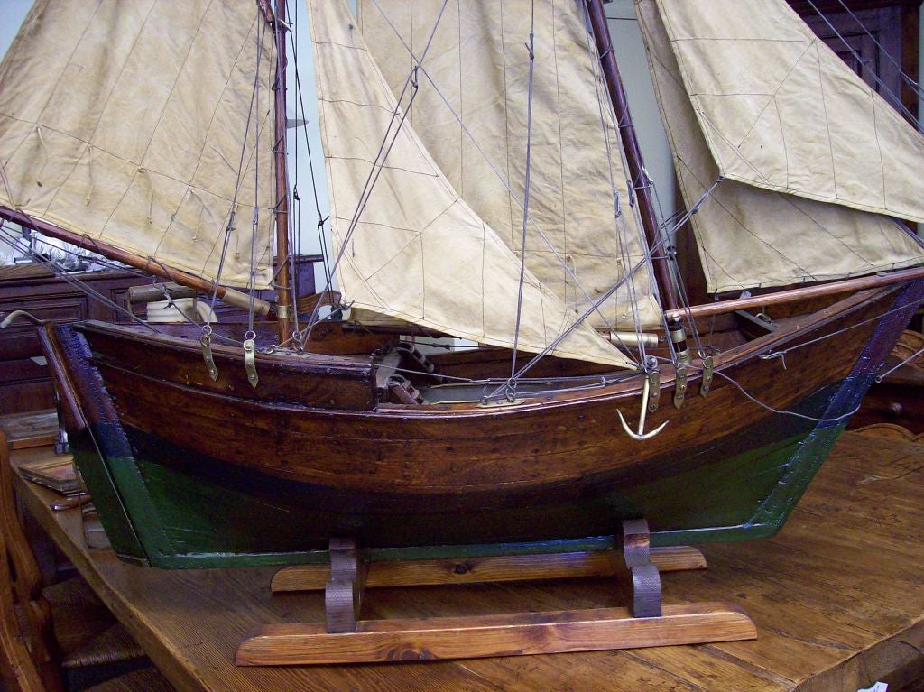 A very large antique English pond yacht model. The wide hull has a beautiful shape and a lovely patina. The sails are great with two nice flags.  Dimensions include the newly made stand.