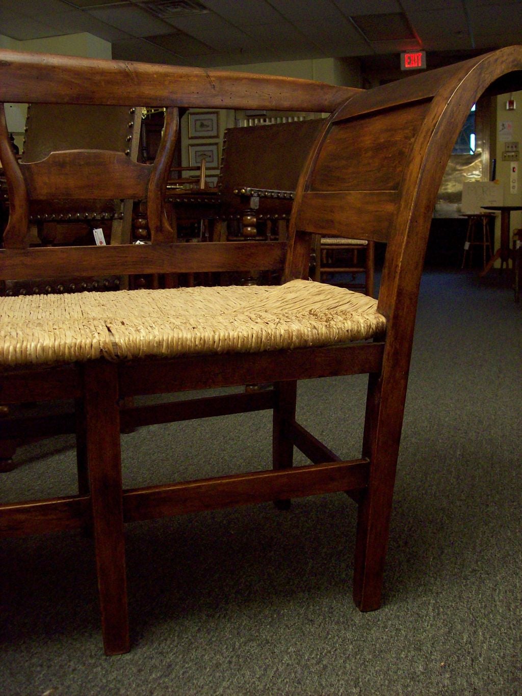 Antique rush seated bench from France. Graceful curved arms and shaped back rails. Fruit wood has a warm patina. Seats four.