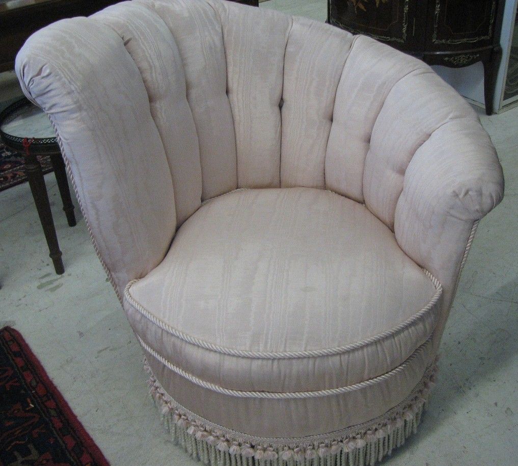 Very comfortable swivel chairs upholstered with pink moire fabric and trimmed with rope and tassels at base.