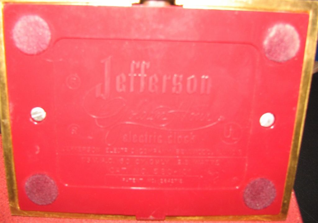 Vintage electric clock from the Jefferson Co. in Bellwood, Illinois. Constructed of gold brushed metal with red bakelite<br />
underneath the base and roman numerals encircling the outer frame.