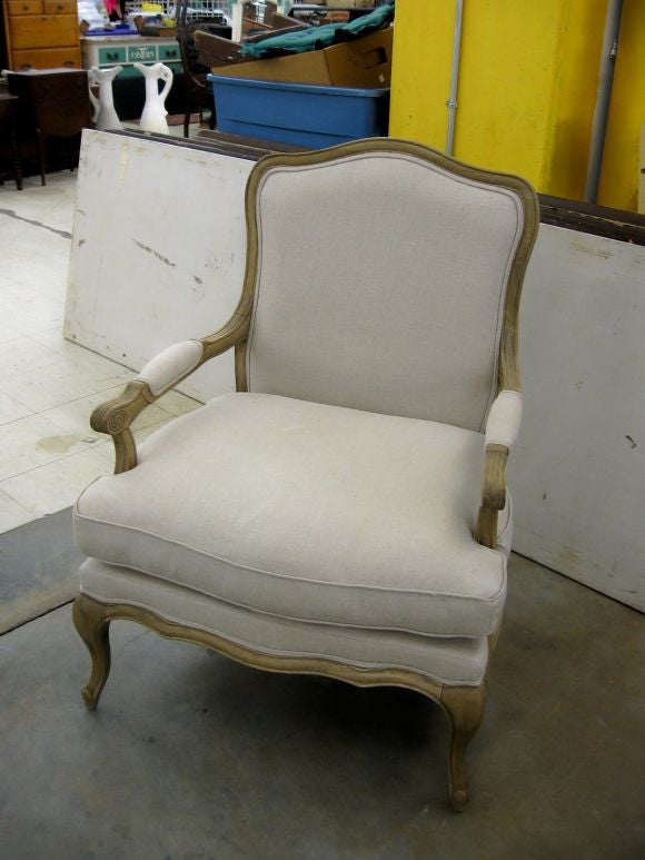 Pair of Louis XV style fauteuil chairs with matching ottomans.  Chairs and ottomans have a natural color wood frame and feather and down cushions.  All have been newly upholstered in an oatmeal colored linen blend.<br />
Dimensions of ottoman are