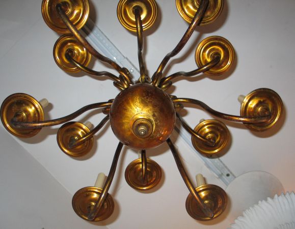 A Classic, sober, Italian midcentury solid brass chandelier with 12 arms on two levels centered around a large brass ball.

The height of 30