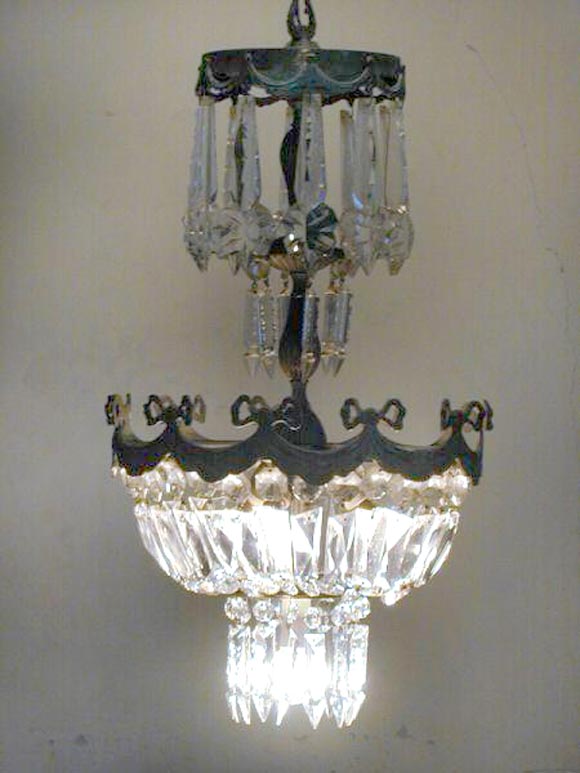 Mid-Century Modern neoclassical chandelier / pendant in the style of Louis XVI with silvered bronze frame and cut crystal decoration in an elongated form. There is a motif of hanging ribbons in the silvered bronze and beautiful cuts in the crystal.