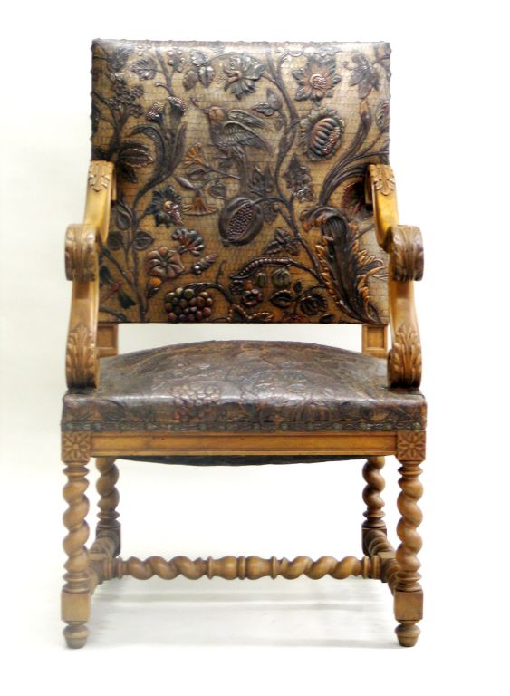 A rare hand-tooled leather armchair or lounge or club chair in the Louis XIII style. The frame is in solid walnut and in a Classic barley twist pattern. The seat and back are hand-tooled with lush nature scene featuring birds, flowers and fruits.