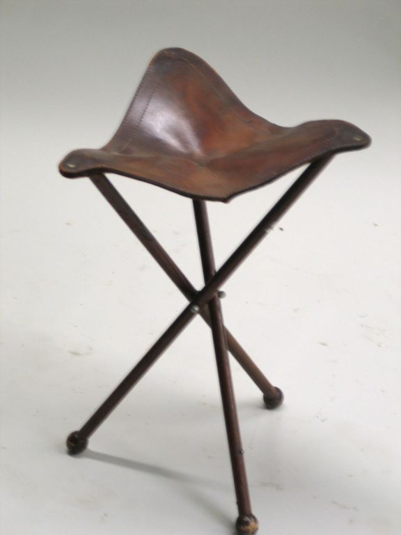 A Classic folding stool in iron with a leather seat.