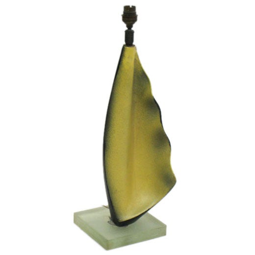 A French midcentury organic form table lamp with an exotic sculptural form. This piece reads differently from every angle due to its combination of unique form and black/yellow glaze technique. It rests on a base of sand-cast glass by Saint Gobain.