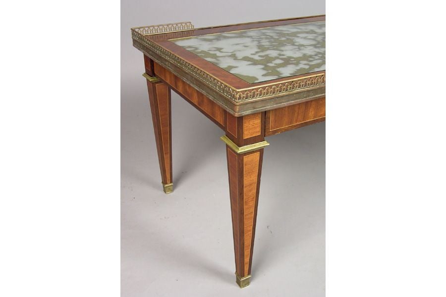 An elegant French Mid-Century Modern neoclassical gilt bronze bound and inlaid Cocktail table by Maison Jansen in the Louis XVI style. The table has the highest level design and workmanship including gilt bronze banding and gallery surrounding the