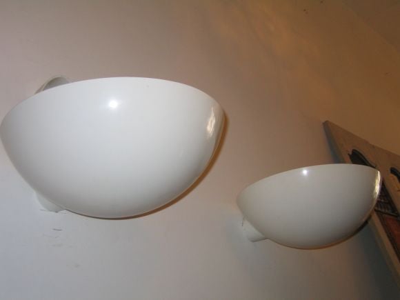 Four sober and elegant Italian Space Age white enameled metal wall lights in the form of a demilune and capable of providing subtle light to a large area. There are both simple and striking, a clean and practical modern statement.

Priced