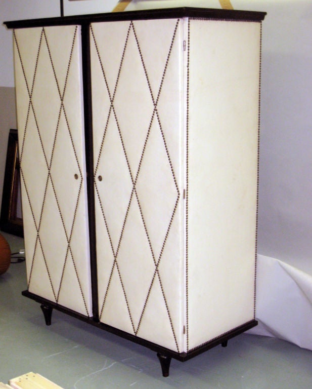 Elegant White 'Leather' Armoire/Storage. A Chic Piece Composed of Dark Stained Walnut which Stands in Contrast to a White Leather-like Covering Studded to Form Chevron Configurations. A Classic French Forties Piece with an Interior Suitable for