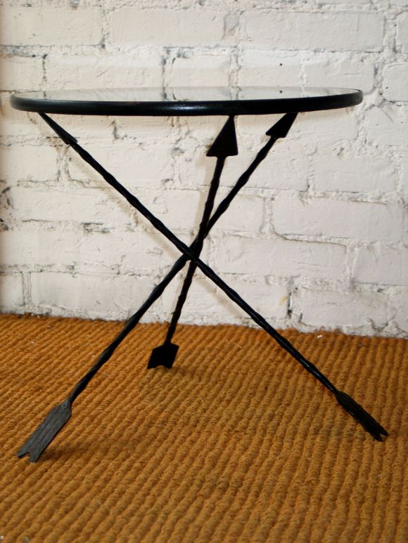 French 1940s gueridon or end table in iron that is patinated black. The black glass top is supported by three legs in the form of arrows.
