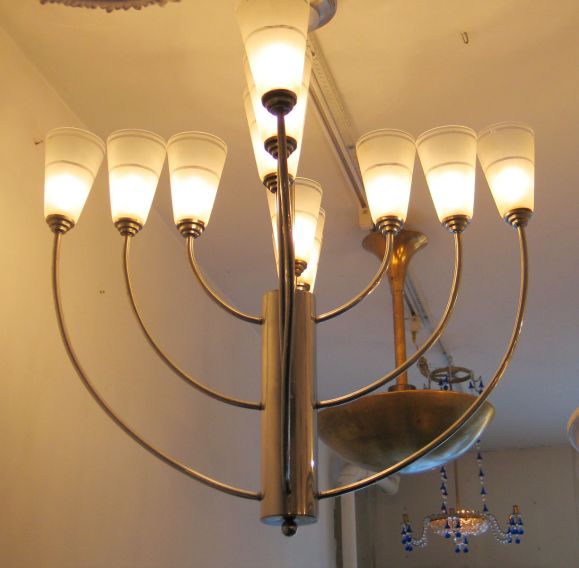 Dramatic French Art Deco twelve-arm chandelier composed of three parallel levels of nickeled metal and opaline glass shades. The chandelier/pendant can be suspended lower from ceiling if desired.