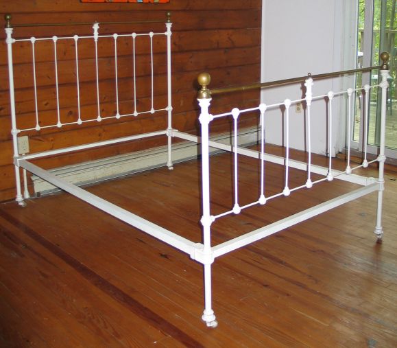 A Late 19th Century Full Size Cast Iron Bed Patinated White with Brass Pediment and Finials. $2,800 Net