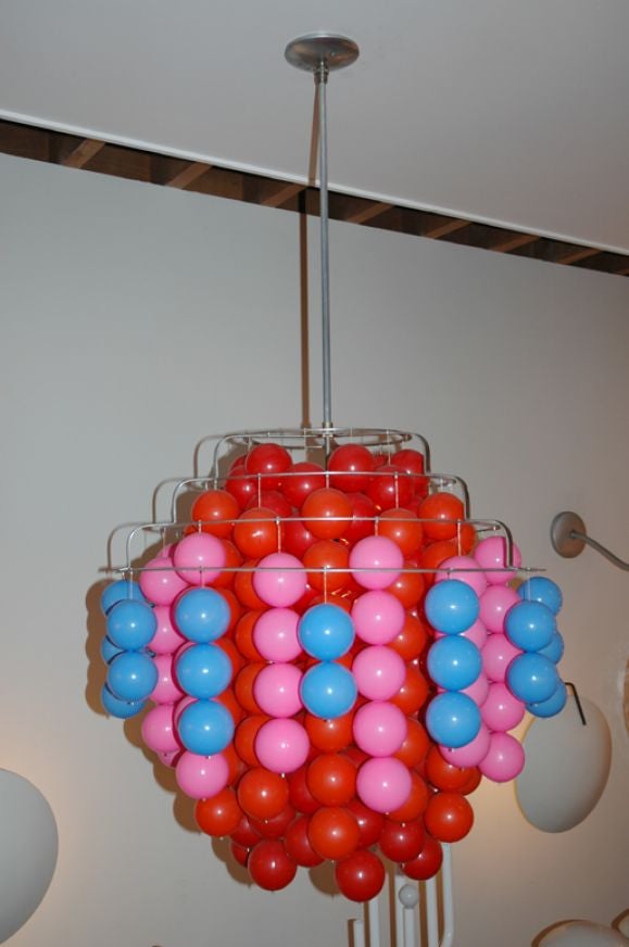 Balls suspended on threads in groups in colors of red, orange pink and blue.