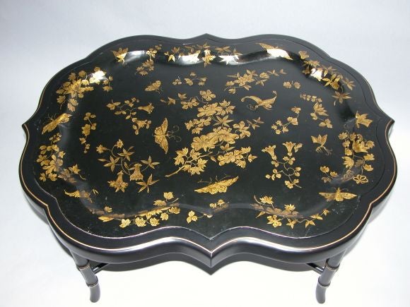 A charming English Victorian black painted tole tray adorned with delicate floral vines and butterflies; raised on later ebonized stand