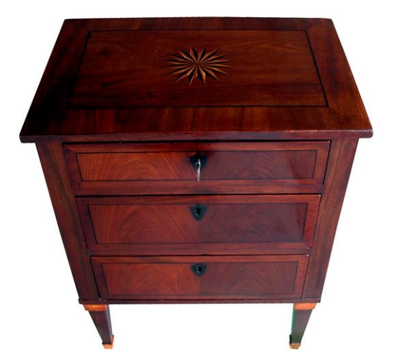 A handsome Norwegian empire three-drawer mahogany commode with ebony stringing and escutcheons; the top centering an inlaid stylized floral motif