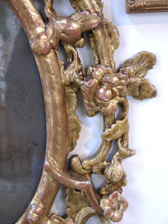 Miroir de forme ovale en bois doré de style George II, bien sculpté, surmonté d'une crête audacieuse représentant un oiseau hoho entouré d'une vigne feuillagée vivante.