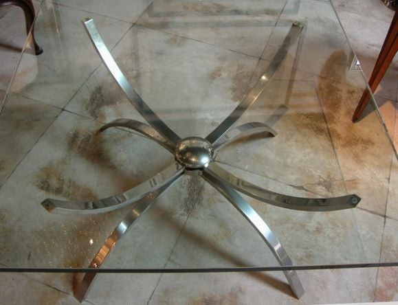 A chic Italian, 1960s nickel-plated cocktail table with square clear glass top; the square clear glass plate resting on a nickel-plated base consisting of 4 upturned supports over 4 downturned legs.